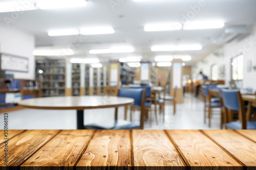 Empty wooden desk space platform with library background for product display montage. Education concept.