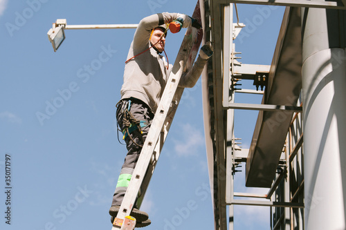 Industrial climber in helmet and overall working on height. Risky job. Professional worker © beatleoff