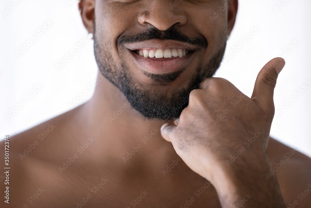 Crop close up of happy african American young man touch beard stubble after  shaving in bathroom, smiling biracial male satisfied with shaved bristle  after shower in bath, body hygiene concept Photos