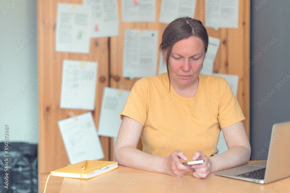 Female freelancer working on smartphone in home office Female freelancer working on smartphone in home office