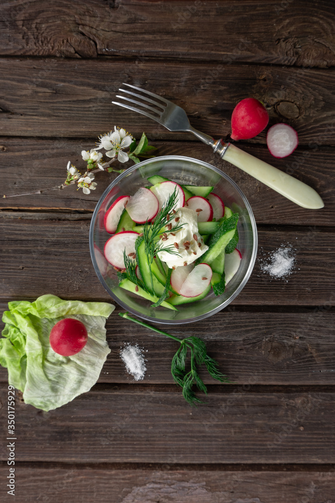 Top view of radish and cucumber salad in a glass bowl on wooden background Top view of radish and cucumber salad in a glass bowl on wooden background