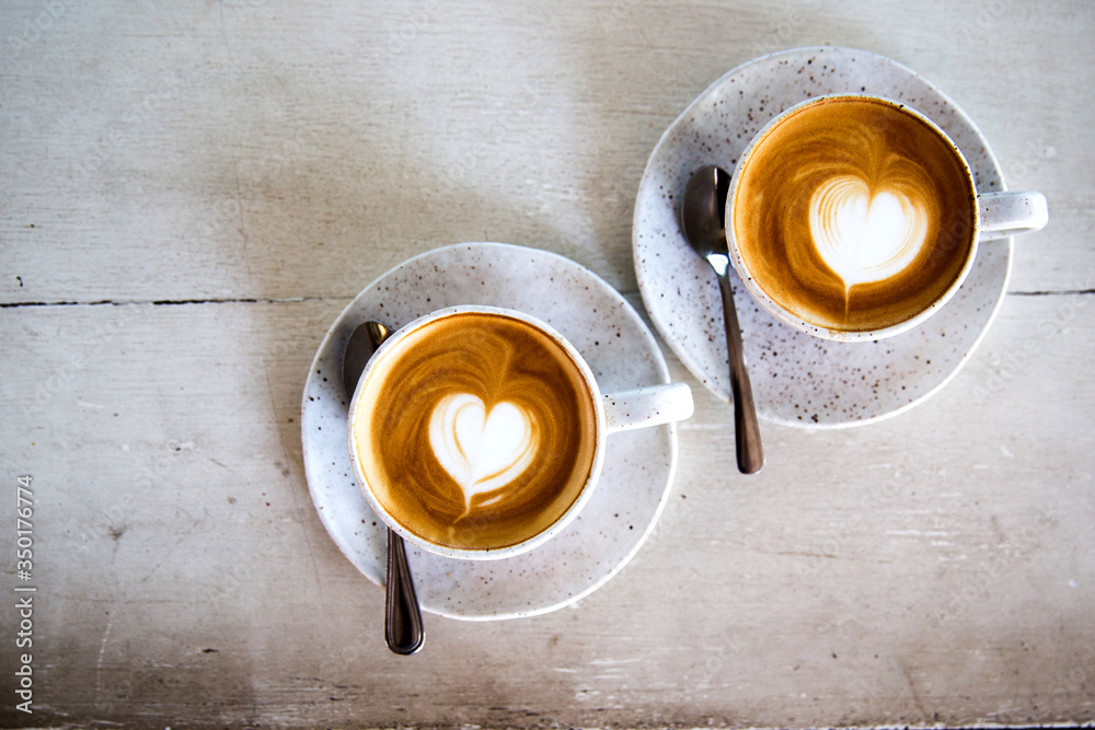 Two Cups of hot cappuccino on white wooden table background. Two Cups of hot cappuccino on white wooden table background.