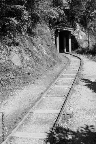 Rail tracks leading into an old mining tunnel. Black and white © Michael