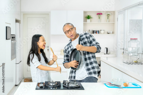 Father and child playing kitchenware like music tool
