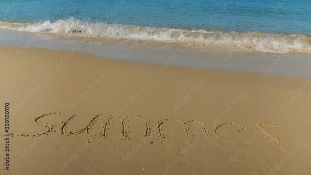 inscription in the sand. Sea wave is approaching the word summer. inscription in the sand. Sea wave is approaching the word summer.