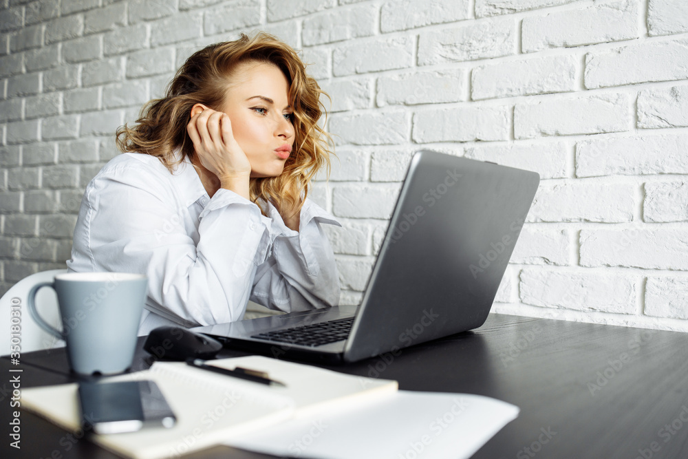 Side view of woman with curly hair sitting at table with laptop. Side view of woman with curly hair sitting at table with laptop.