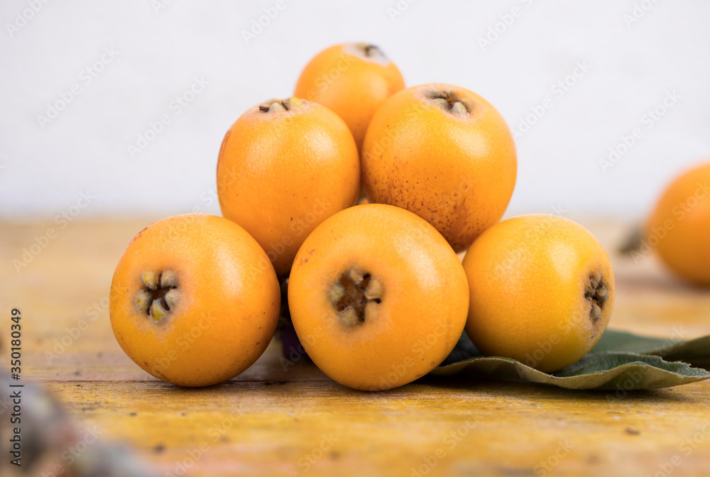 Fresh loquats, recently recolted from a trea lay on a wooden textured table. Beautiful rustic image