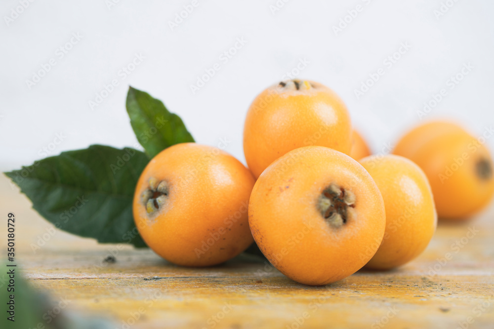 Fresh loquats, recently recolted from a trea lay on a wooden textured table. Beautiful rustic image