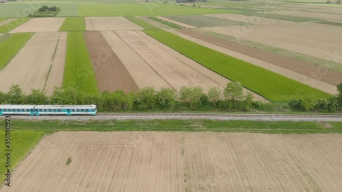Fast train cross the agricultural field on an isolate railway far away from the city bringing worker to their job. photo