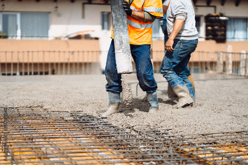 caucasian workers pouring concrete with concrete pump. Details of construction site and close up details of worker workwear