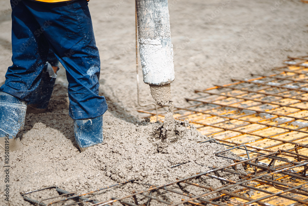 Construction worker working on building a house. Worker and cement pump Construction worker working on building a house. Worker and cement pump