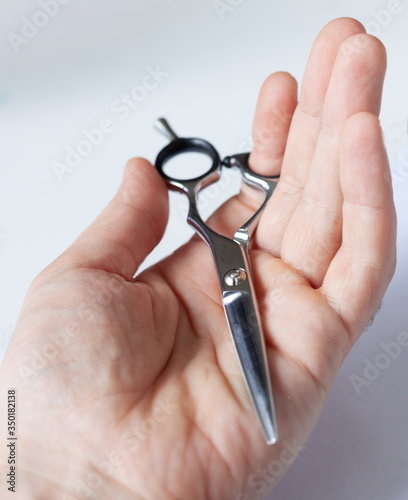 hand holds hairdressing scissors close-up  on a white light background