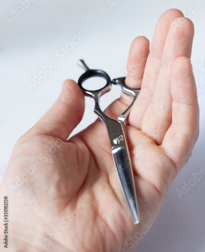 hand holds hairdressing scissors close-up, on a white light background