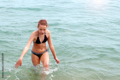  girl in a swimsuit comes out of the sea 