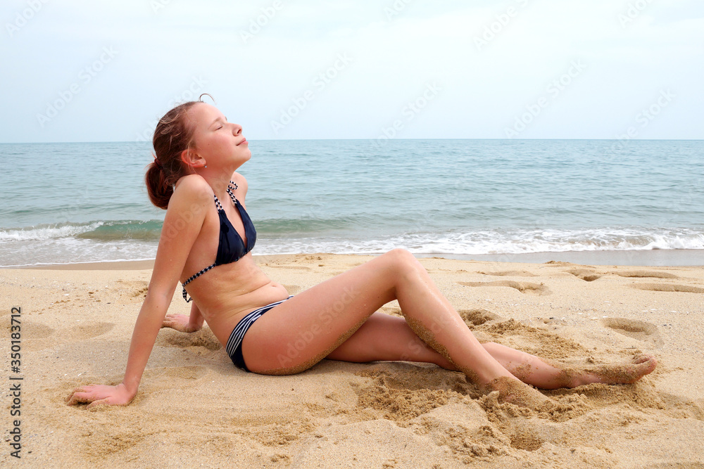 girl in a swimsuit sunbathes on a sandy beach against the background of the sea
girl in a swimsuit sunbathes on a sandy beach against the background of the sea