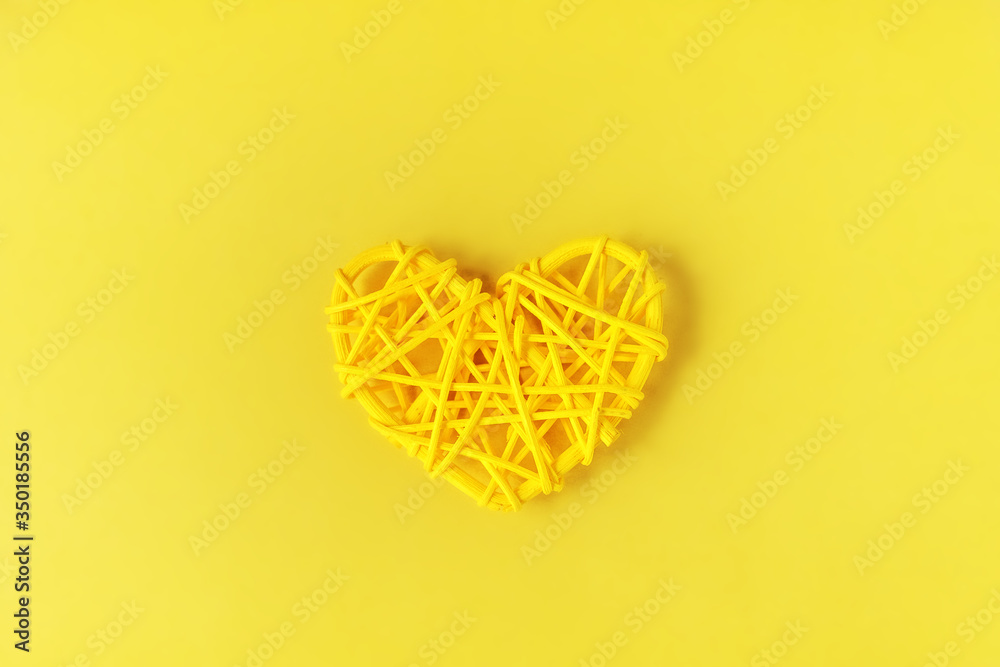 Yellow rattan wicker heart on a yellow background.Symbol of love.Valentine's Day