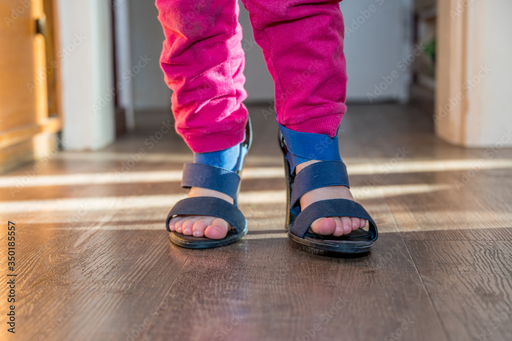 Detail view of young girl walking in her mother high heel shoes. Detail view of young girl walking in her mother high heel shoes.