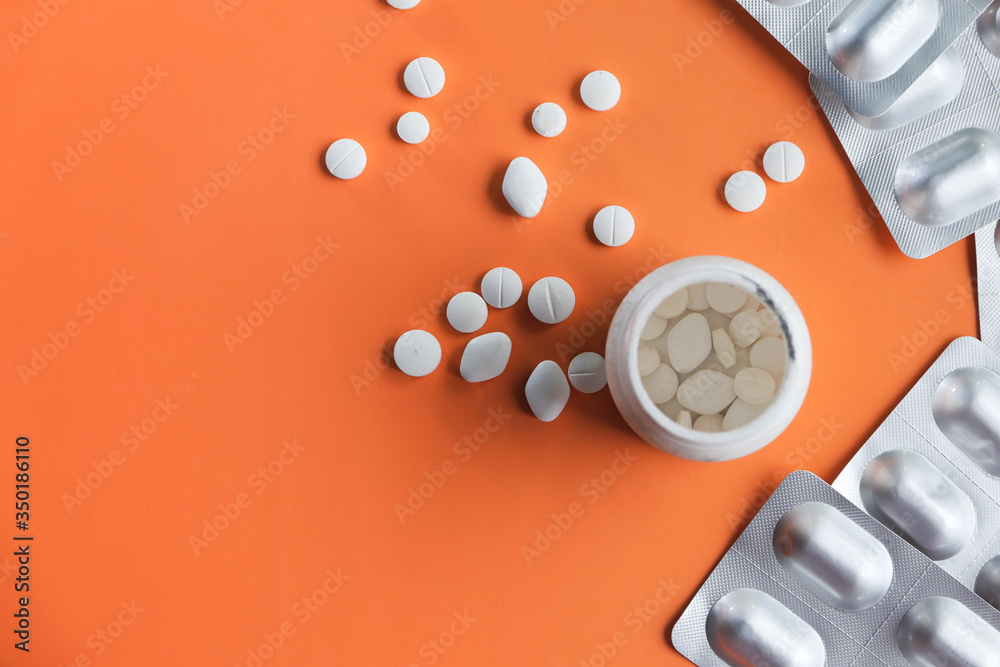 bottle of white pills on orange background 