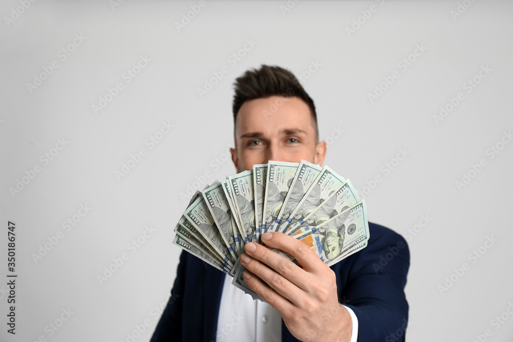 Happy man with cash money against light grey background, focus on hand Happy man with cash money against light grey background, focus on hand