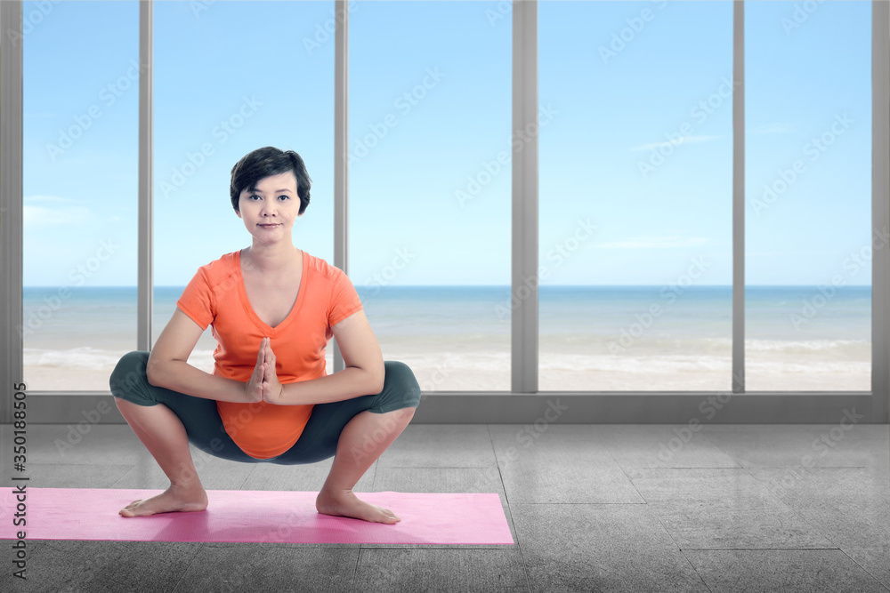 Asian pregnant woman is practicing yoga in a yoga mat at home Asian pregnant woman is practicing yoga in a yoga mat at home