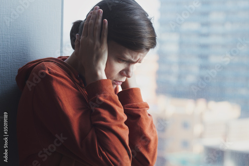 mental health, stress, migraine or depression concept, young sad depressed frustrated autistic woman sitting at home alone suffering from head ache and psychological problems photo