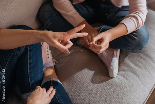 Cropped view of mother and daughter playing rock paper scissors on couch