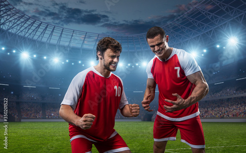 Happy soccer players celebrate a victory on a professional football stadium