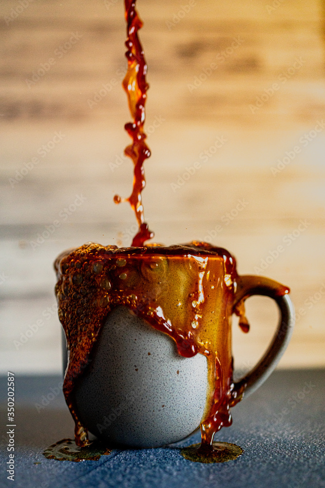 Overflowing cup of coffee with gray mug. Stock Photo