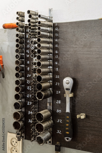 Tools on the board. Spanners hanging on wall in workshop.