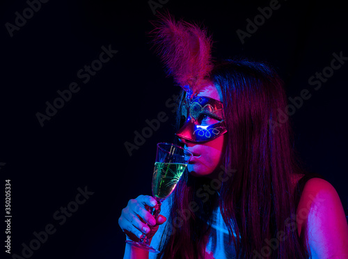 A woman in mask in a bar with a liquor cup
