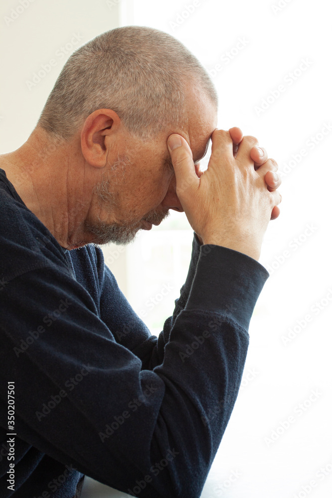Unhappy depressed male sitting by a table stressed from work, anxiety, heartbroken and health care concept. Close up portrait. Unhappy depressed male sitting by a table stressed from work, anxiety, heartbroken and health care concept. Close up portrait.