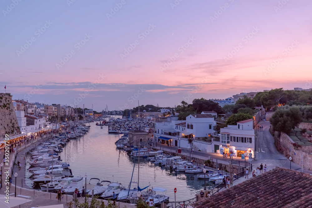 View of the old port in town Ciutadella with boats and restaurants (beautiful evening light)