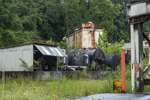 Fotografie Old abandoned vintage industrial machinery covered in kudzu and grass in urban A