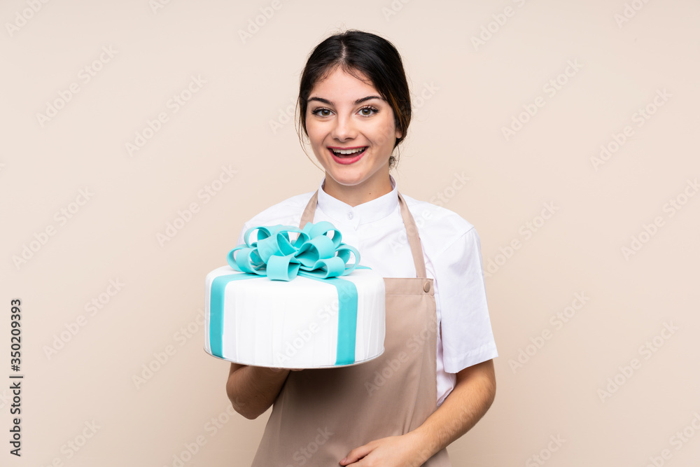 Pastry chef woman holding a big cake over isolated background with surprise and shocked facial expression Pastry chef woman holding a big cake over isolated background with surprise and shocked facial expression