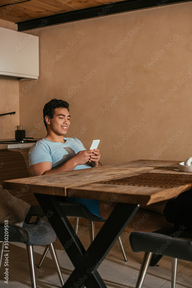 young mixed race man chilling and using smartphone on kitchen during quarantine young mixed race man chilling and using smartphone on kitchen during quarantine
