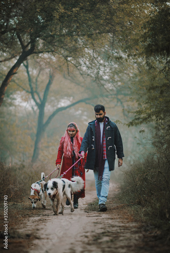 A happy couple in love, with their pet dogs in a forest.
