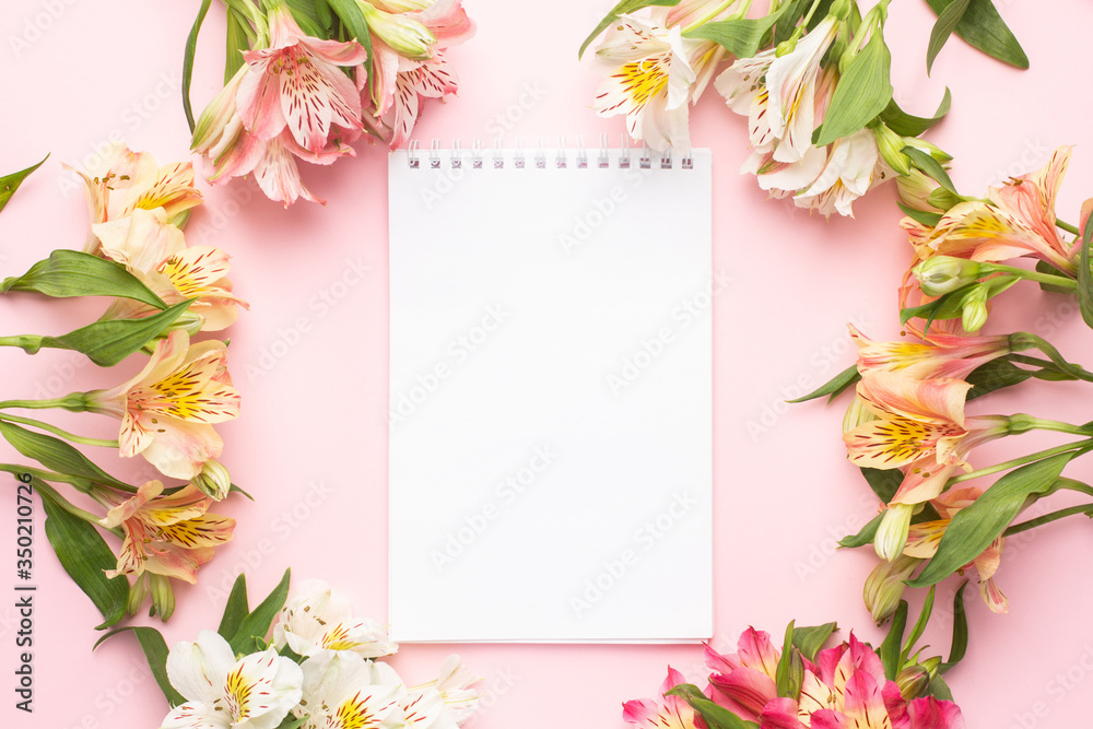Notebook and yellow and pink flowers on a pink background