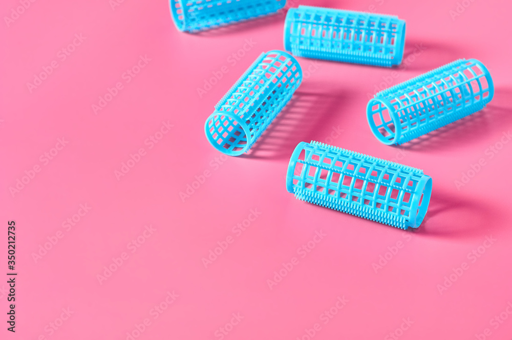 Scattered plastic cylindrical curler on pink desk in beauty salon. Care for hair. Fashion concept Scattered plastic cylindrical curler on pink desk in beauty salon. Care for hair. Fashion concept