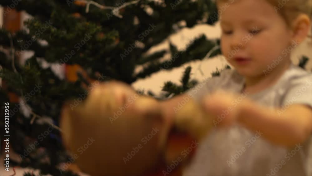 A child plays with a toy owl near the Christmas tree. A child plays with a toy owl near the Christmas tree.