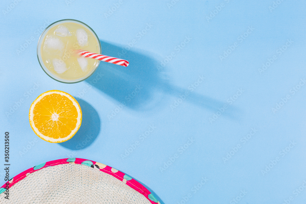 Beach accessories on a turquoise blue background - beach hat, orange fruit, orange juice Summer is coming to a head. Holiday concept by the sea. Holiday accessories map in yellow