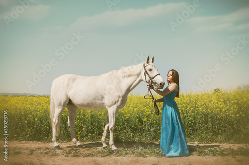 Woman in elegant long dress with gorgeous white horse