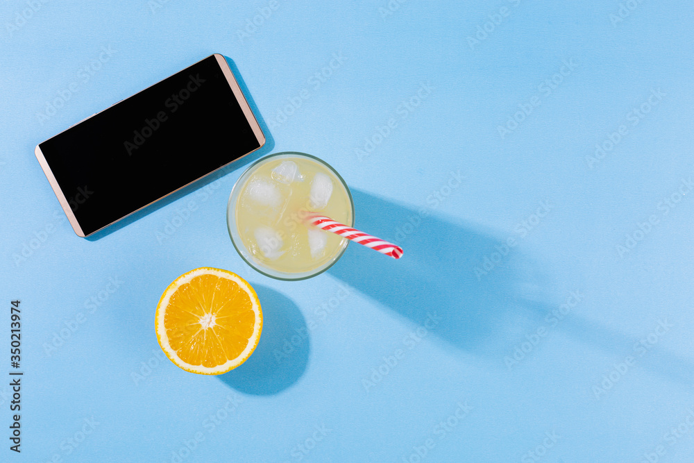 Beach accessories on a turquoise blue background - orange fruit, smartphone, orange juice Summer is coming to a head. Holiday concept by the sea. Holiday accessories map in yellow