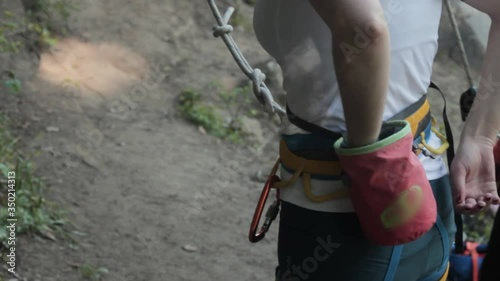 Girl wearing harness using chalk preparing for the climb at the rock