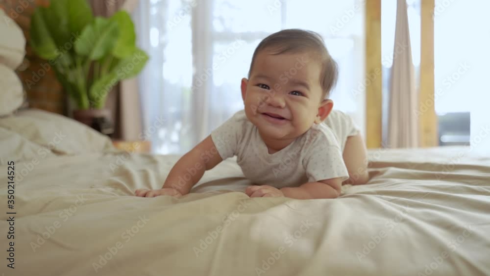 asian baby learn to crawl on the bed. crawling development milestone asian baby learn to crawl on the bed. crawling development milestone
