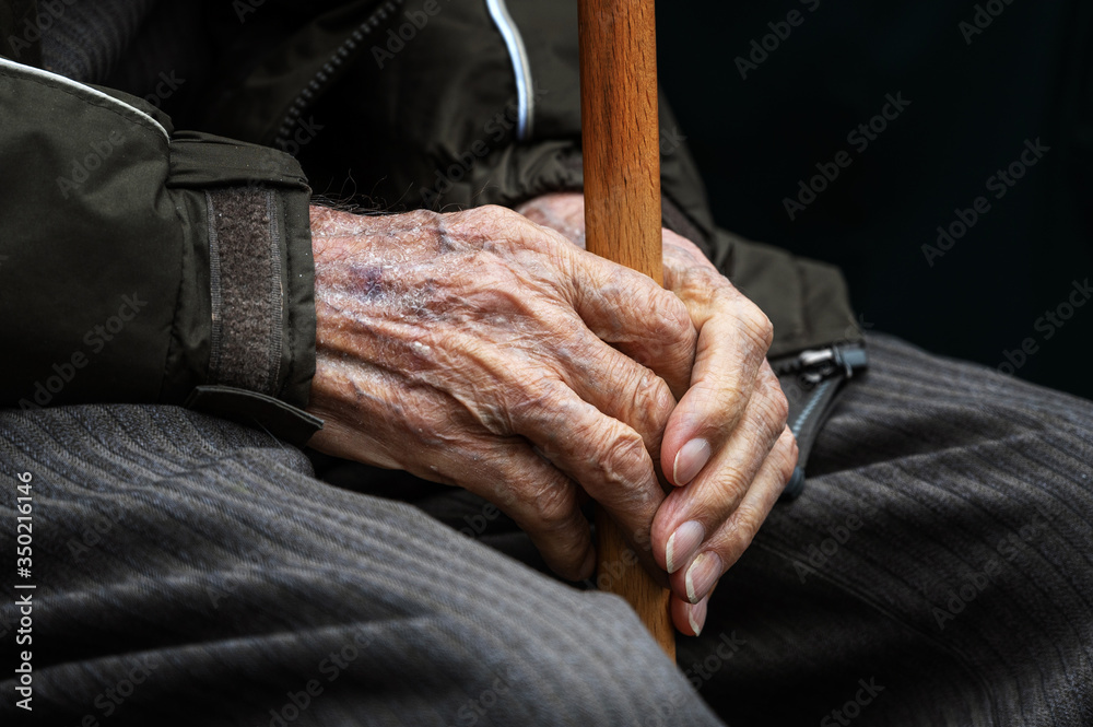 hands of an old sick grandfather with a walking stick. disabled man with a cane. veteran in the parade