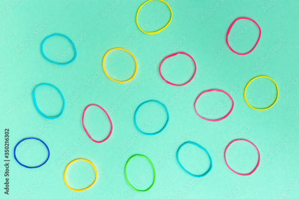 Many colorful elastic bands on plain background.