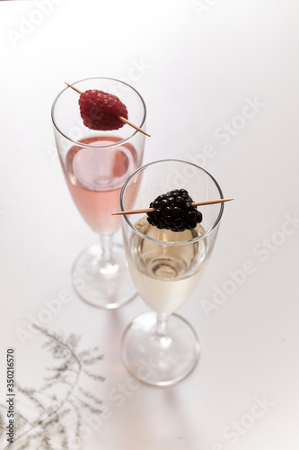 one cocktail with one berry on a white table.