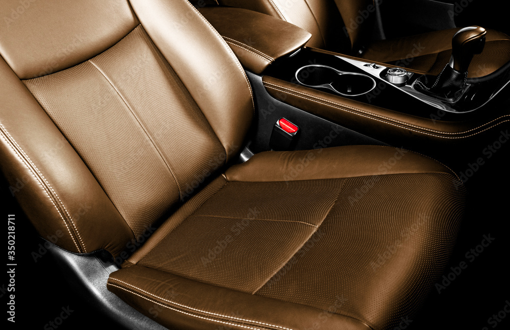 Luxury car brown leather interior. Part of leather car seat details with stitching. Comfortable perforated orange leather seats. Brown perforated leather. Car inside