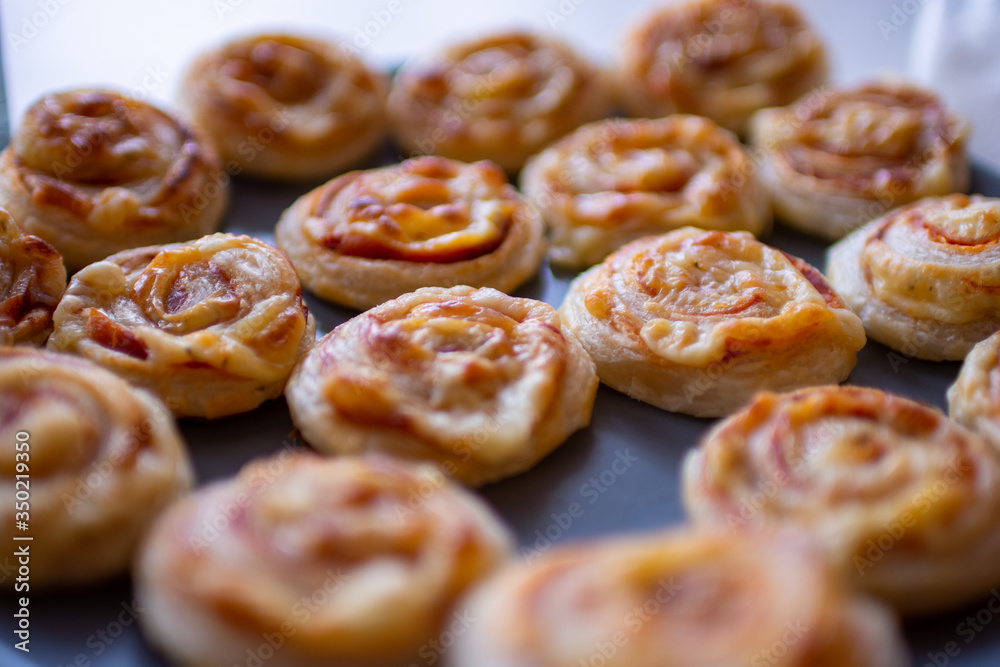 Freshly baked, crispy, salty snails from puff pastry with ham and cheese in the oven