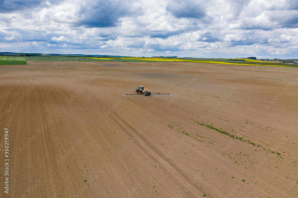 Obraz premium Traktor beim sprühen von Chemikalien auf einem Feld